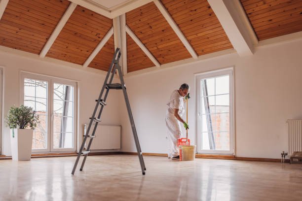 One man, mature male painter painting a wall with paint roller, indoors in a house.