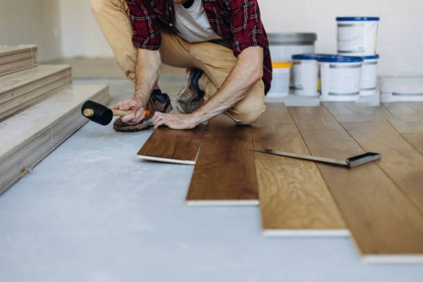 Installing the parquet floor, a man hands fixing one tile with a hammer. House renovation