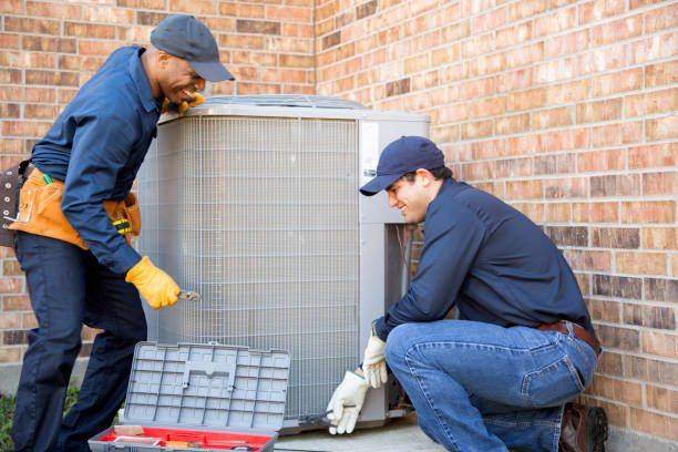 Multi-ethnic team of blue collar air conditioner repairmen at work.  They prepare to begin work by gathering appropriate tools from their tool box.